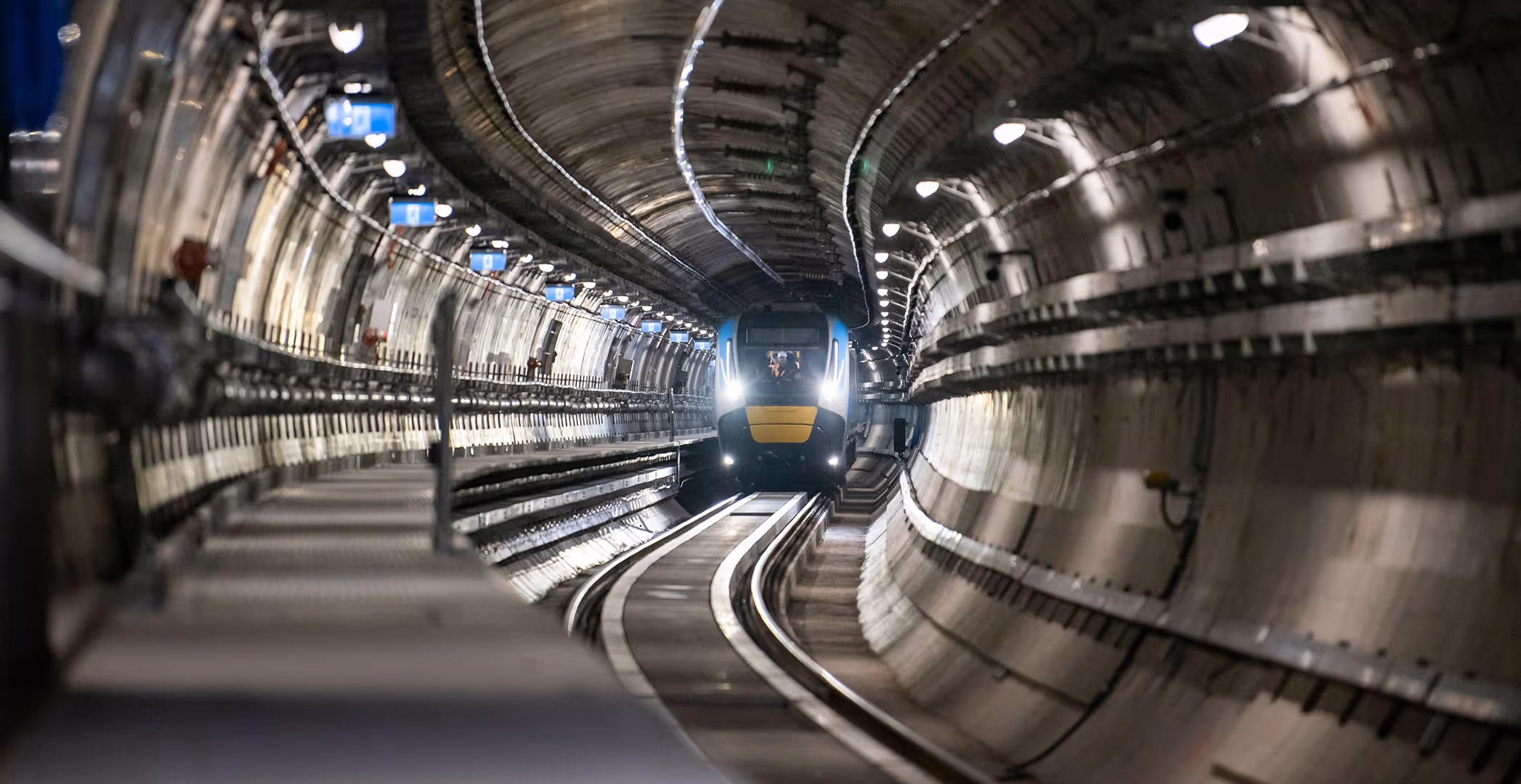 Interior view of Melbourne Metro Tunnel with a test train approaching inside the finished underground rail tunnel.