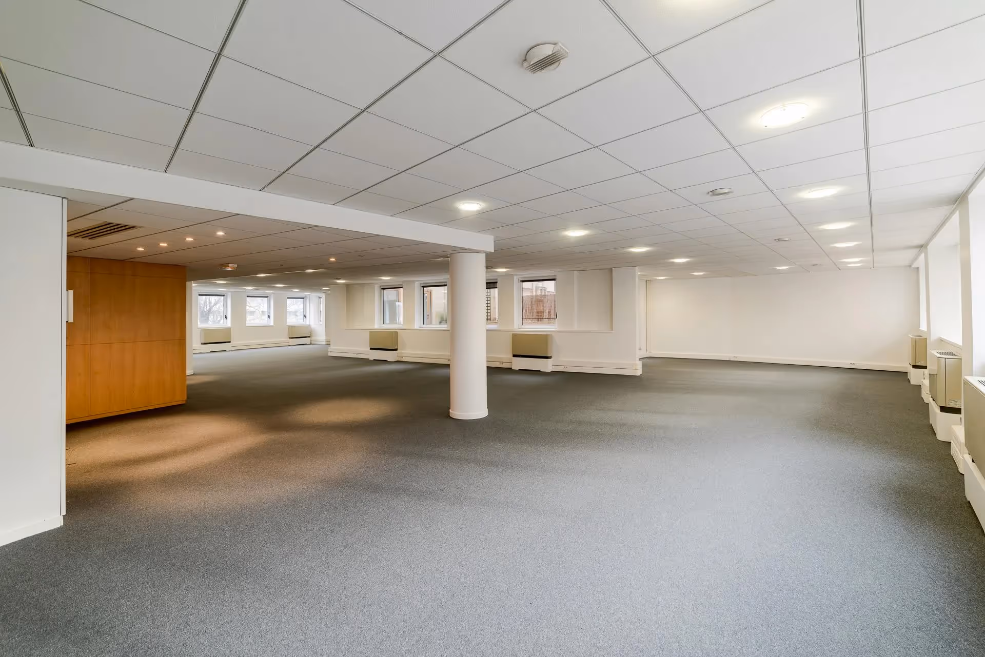 Category A fitout of open-plan office with ceiling tiles and carpeting.