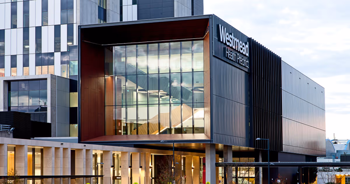 Modern exterior of Westmead Health Precinct showing glass façade, bold structural framing, and signage on the redeveloped hospital building.