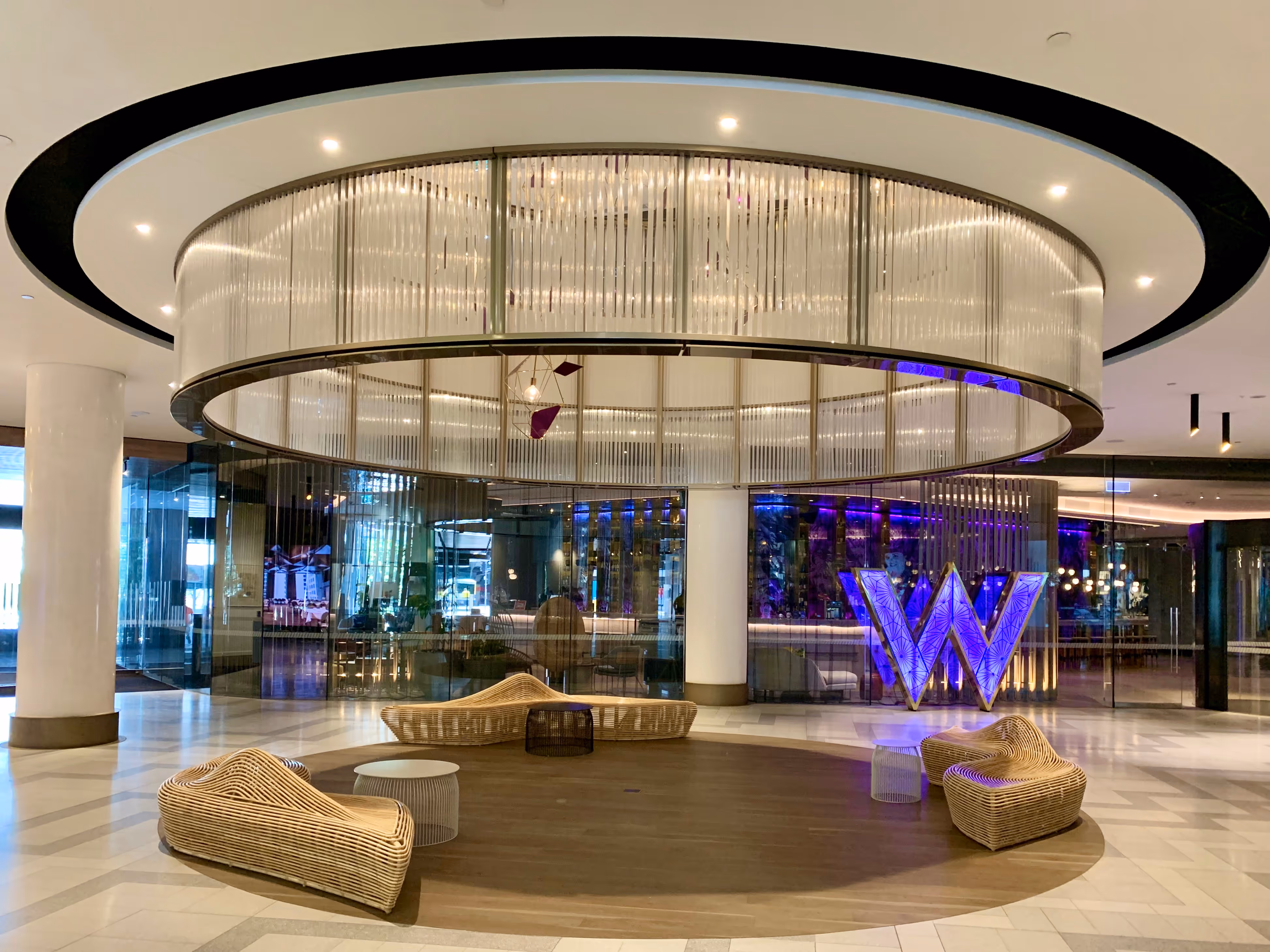 Lobby of W Hotel Brisbane with circular seating area, modern lighting, and a large illuminated “W” sign.