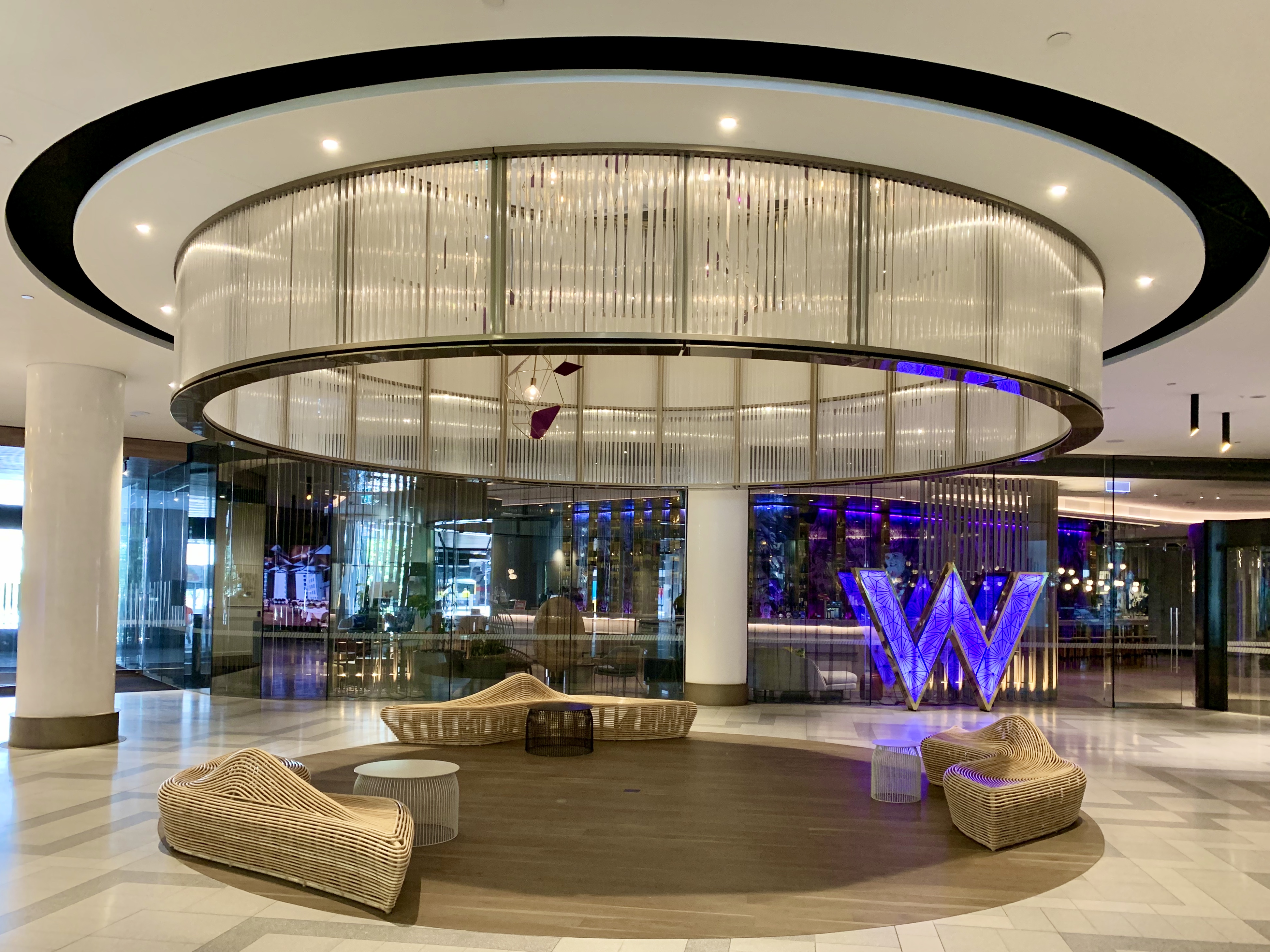 Lobby of W Hotel Brisbane with circular seating area, modern lighting, and a large illuminated “W” sign.