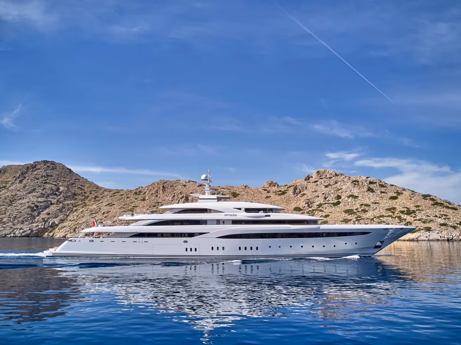 Refitted superyacht O’PTASIA cruising near rocky Mediterranean coastline