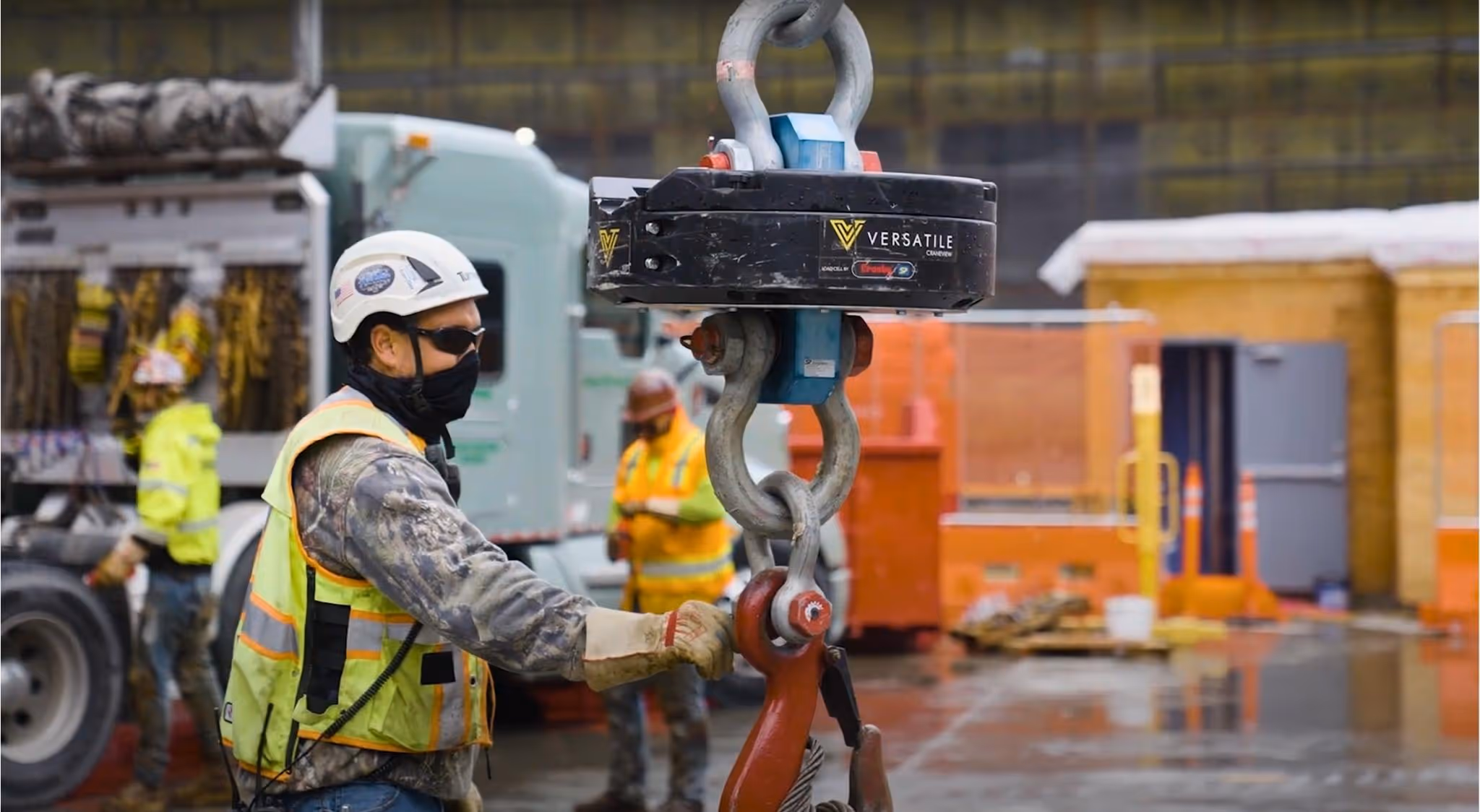 Construction worker attaches heavy load to a crane hook equipped with Versatile's CraneView sensor.