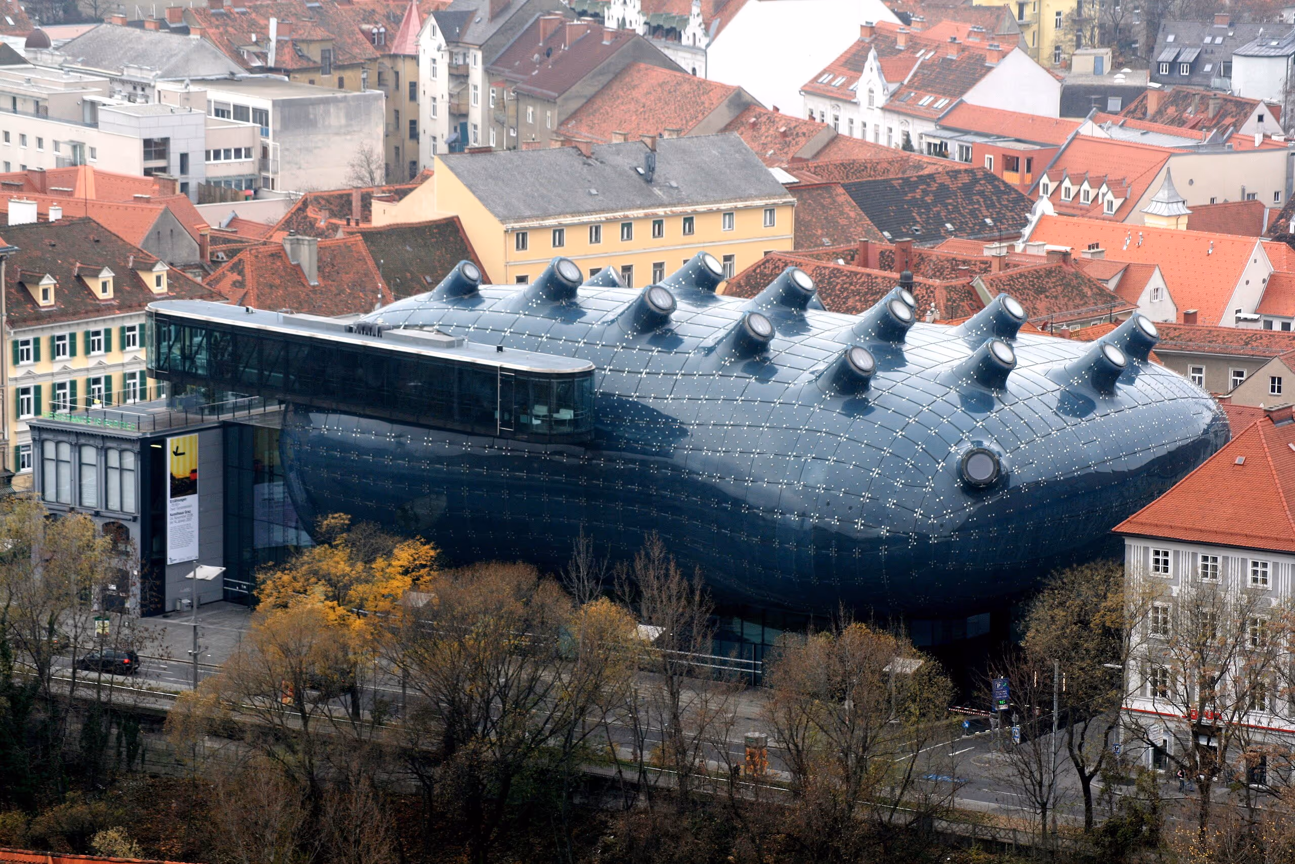 A futuristic, blob-shaped museum with blue reflective panels and nozzle-like skylights on the roof.