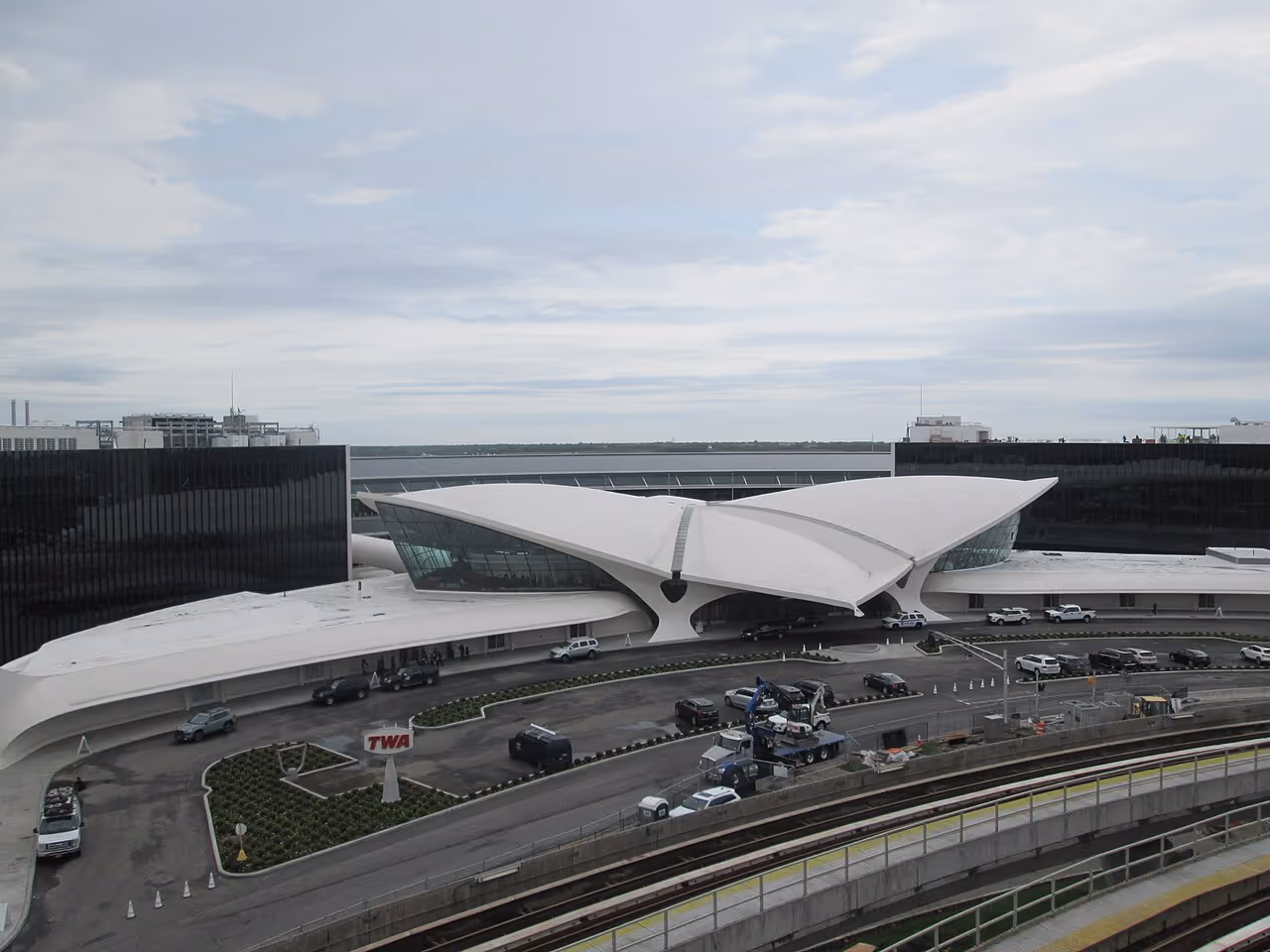A sleek white terminal building with sweeping, wing-like curves, restored as a hotel at an airport complex.