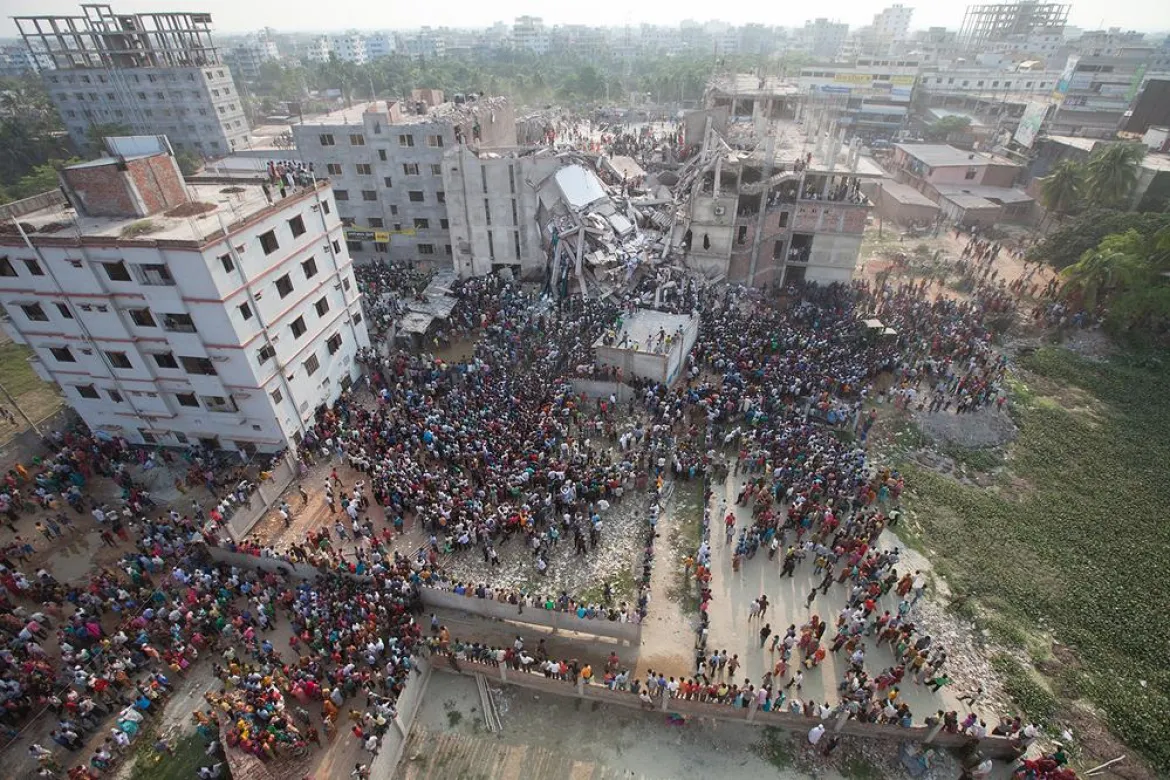 Aerial photo of collapsed buildings surrounded by crowds of people during rescue operations.
