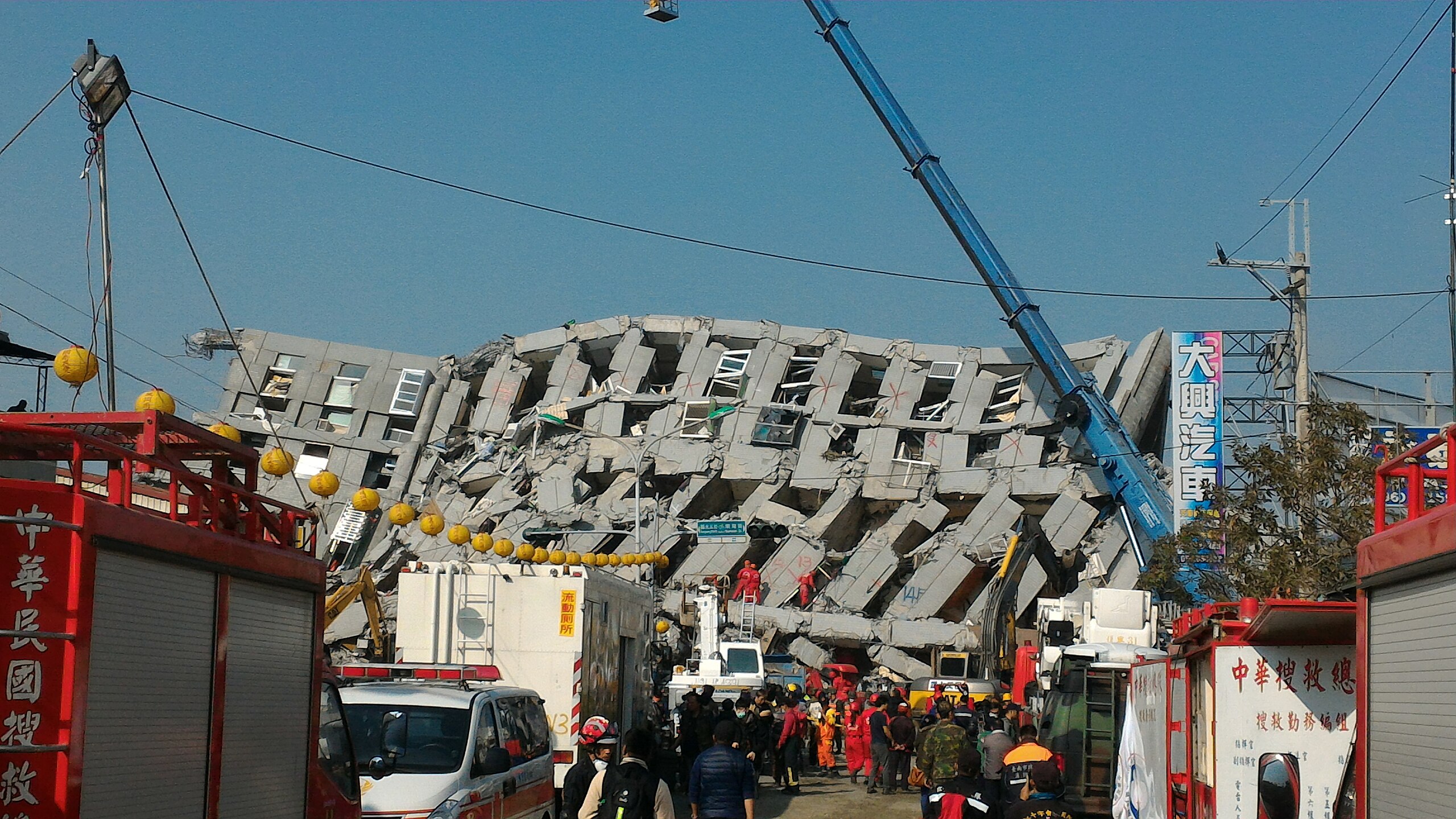 Close-up view of leaning floors and rescue crews in the debris of the Weiguan Jinlong building collapse.
