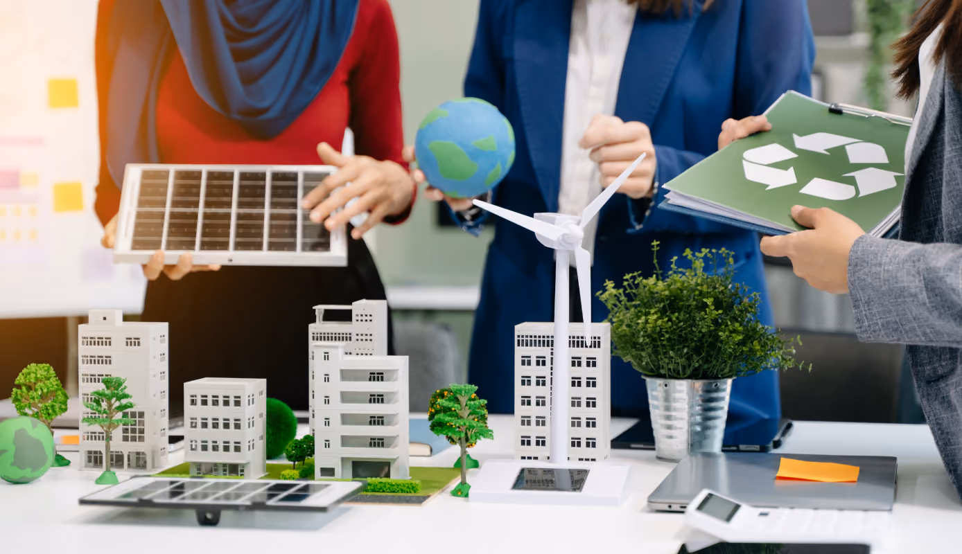 Project team reviewing a sustainable real estate model with solar panels, wind energy, and recycling materials during planning.