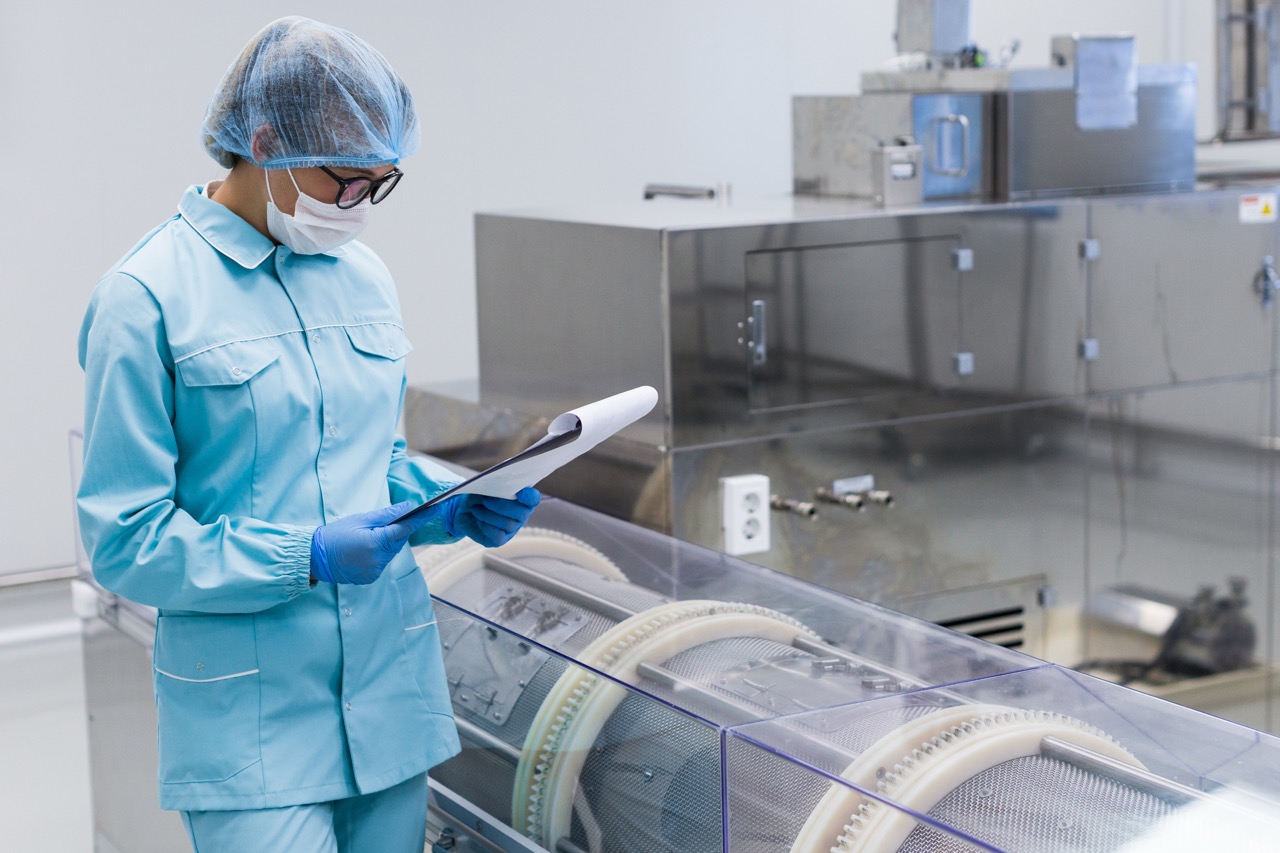 Healthcare worker in protective clothing reviews documents beside sterilization equipment in a hospital CSSD.