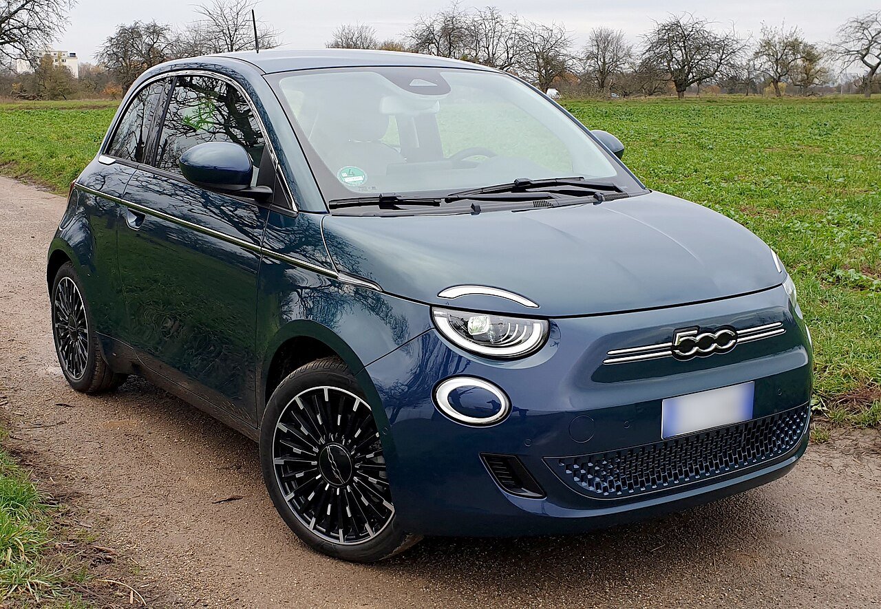 A 2026 FIAT 500e BEV in dark blue, three-quarter front view.