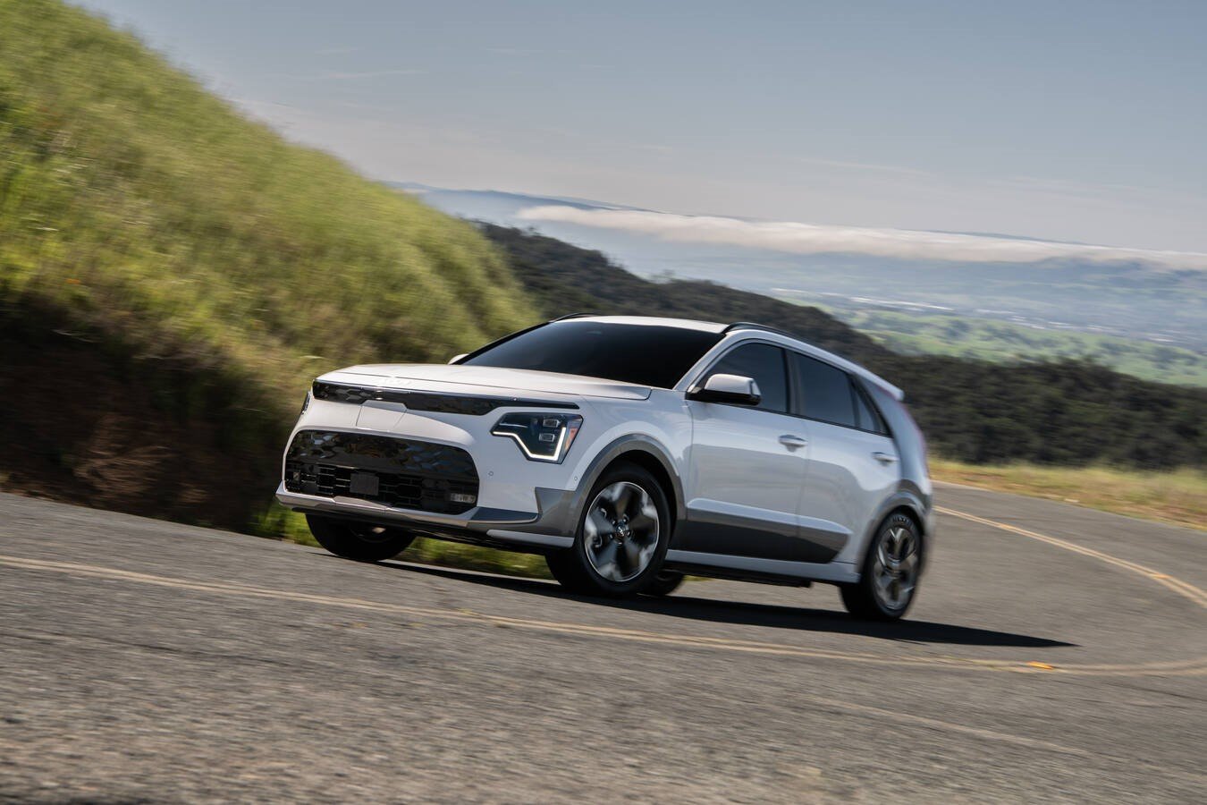 A 2026 Kia Niro EV crossover in sage green, three-quarter front view.