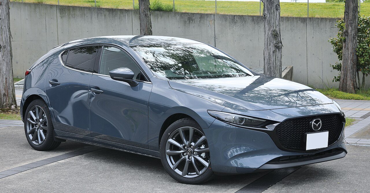 A Mazda3 Sport hatchback in dark grey, three-quarter front view.