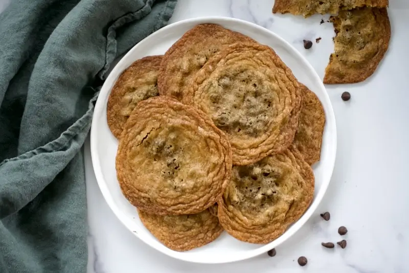 A plate of thin and crispy chocolate chip cookies.
