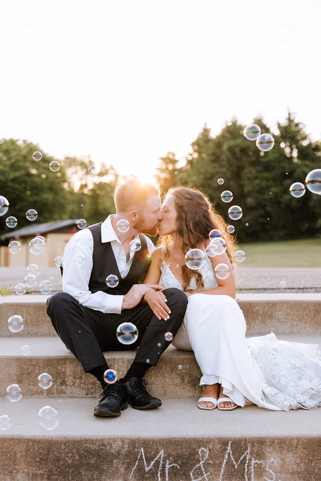 Bride and groom share a kiss during golden hour on the park steps at North Moreland Park in Apollo, PA—great documentary photography.