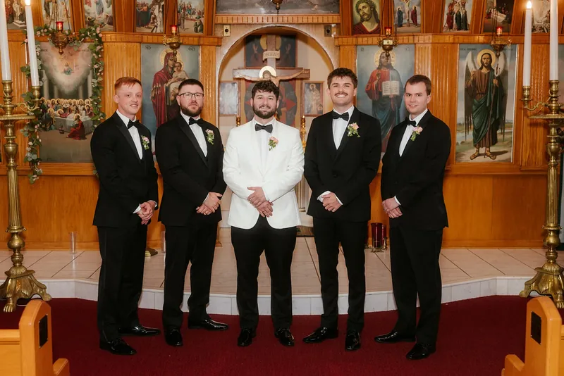 Groom in a white dinner jacket with his groomsmen at the church