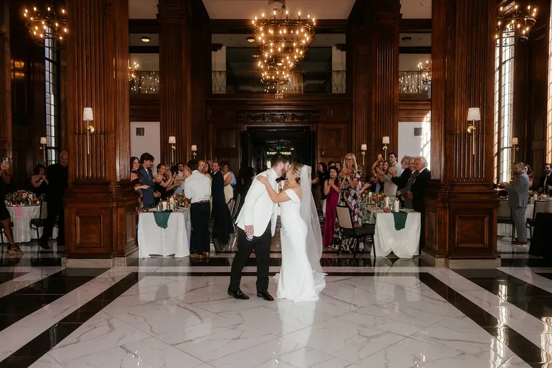 Bride and groom kissing during their reception entrance as guests applaud