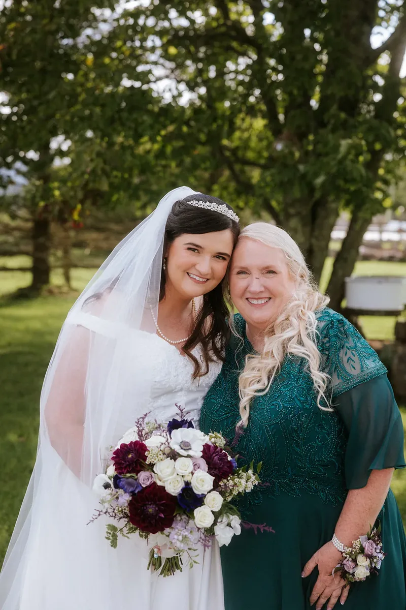 Bride posing with a loved one in a green dress outdoors.