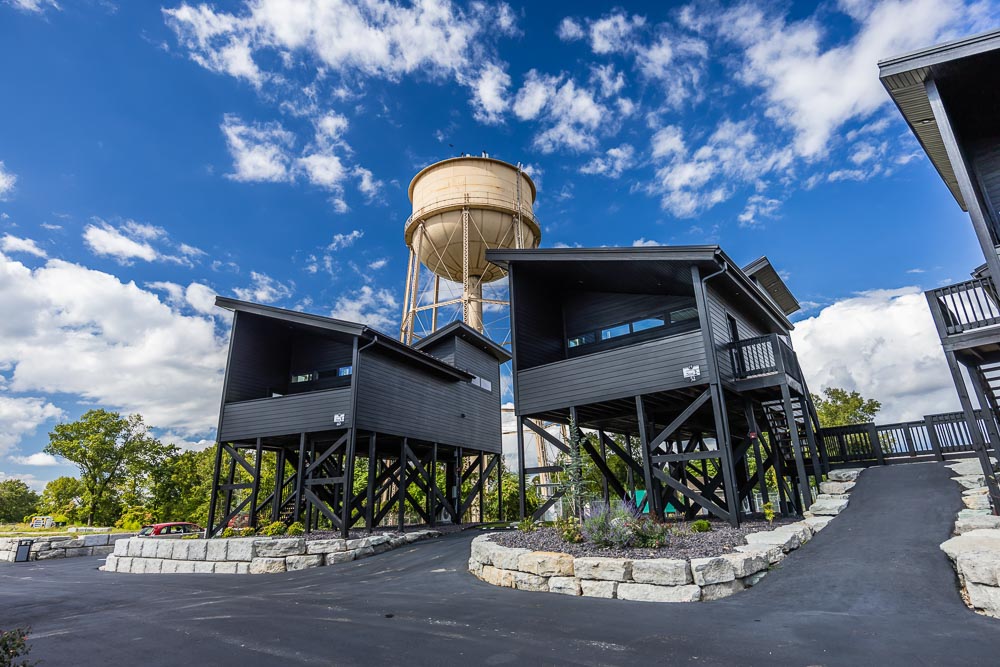 Two Nest treehouse suites on stilts under a blue sky, with the Grotto water tower