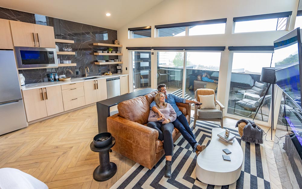 Couple relaxing on a leather sofa in a suite living area with lake-view windows