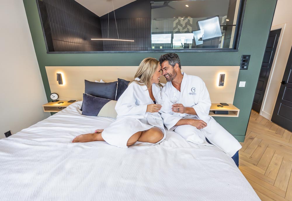 Couple in white robes relaxing on a king bed