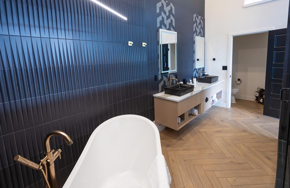 Bathroom with a white soaking tub, brass faucet and black ribbed tile