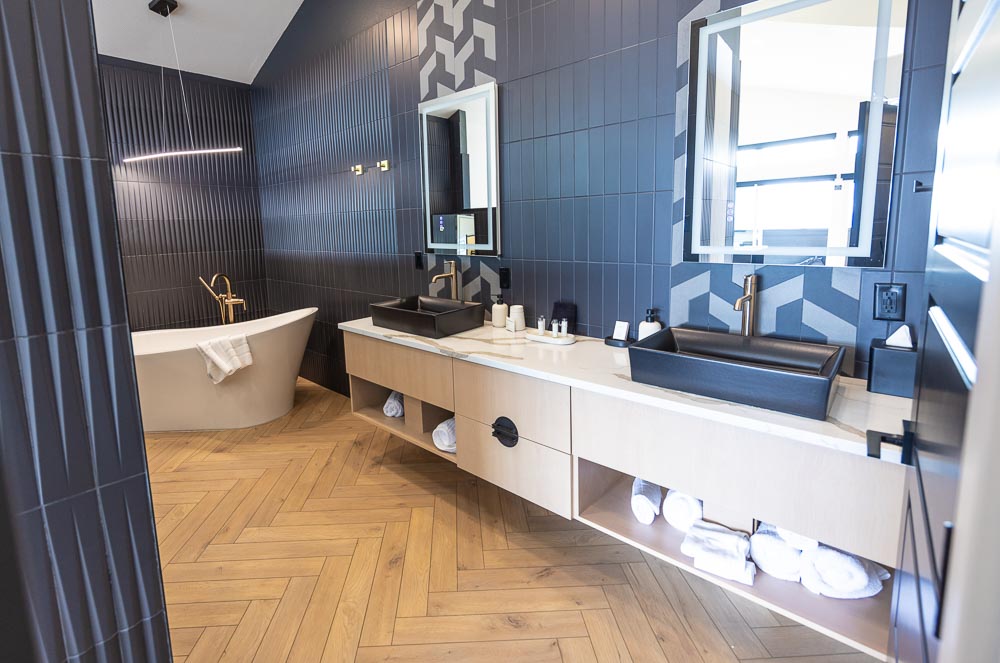Freestanding soaking tub and black vessel sinks in a suite bathroom