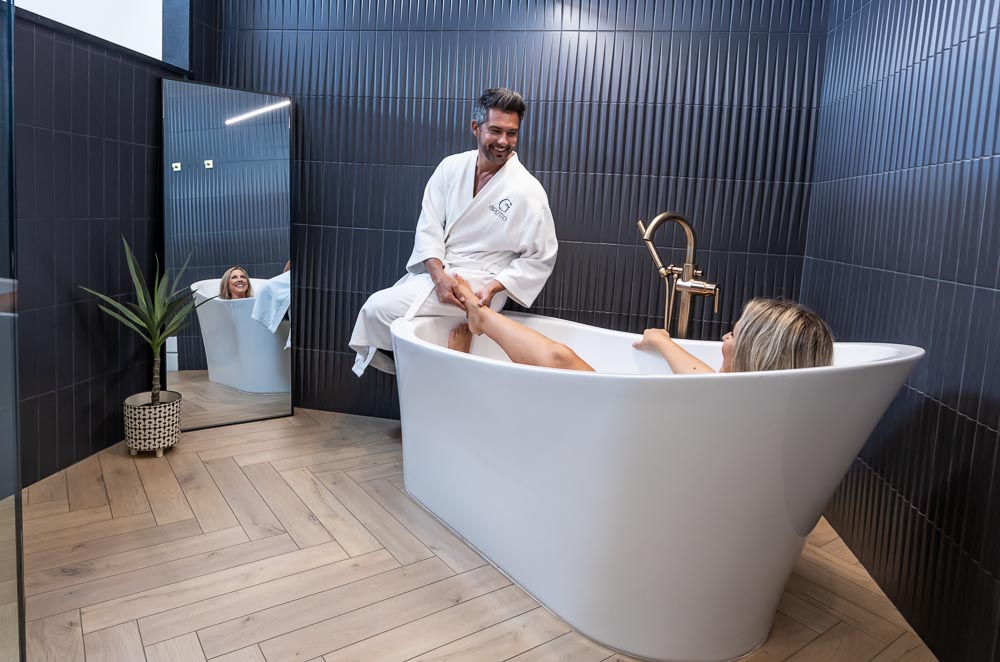 Couple enjoying the freestanding soaking tub in a suite bathroom
