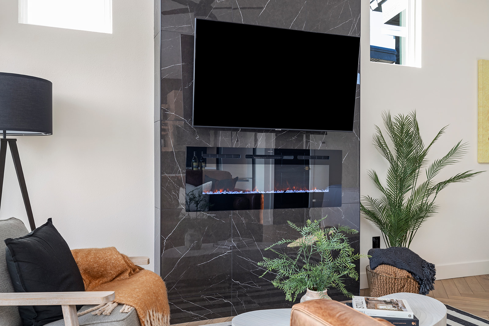 Gas fireplace below a wall-mounted TV with a leather chair and plant