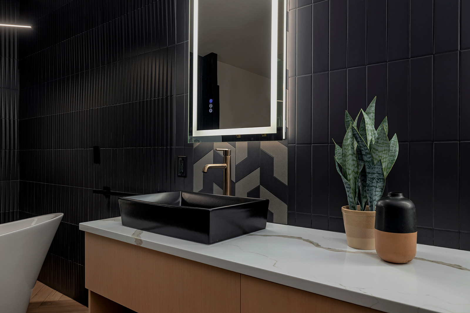 Vanity with black vessel sink, brass faucet and backlit mirror