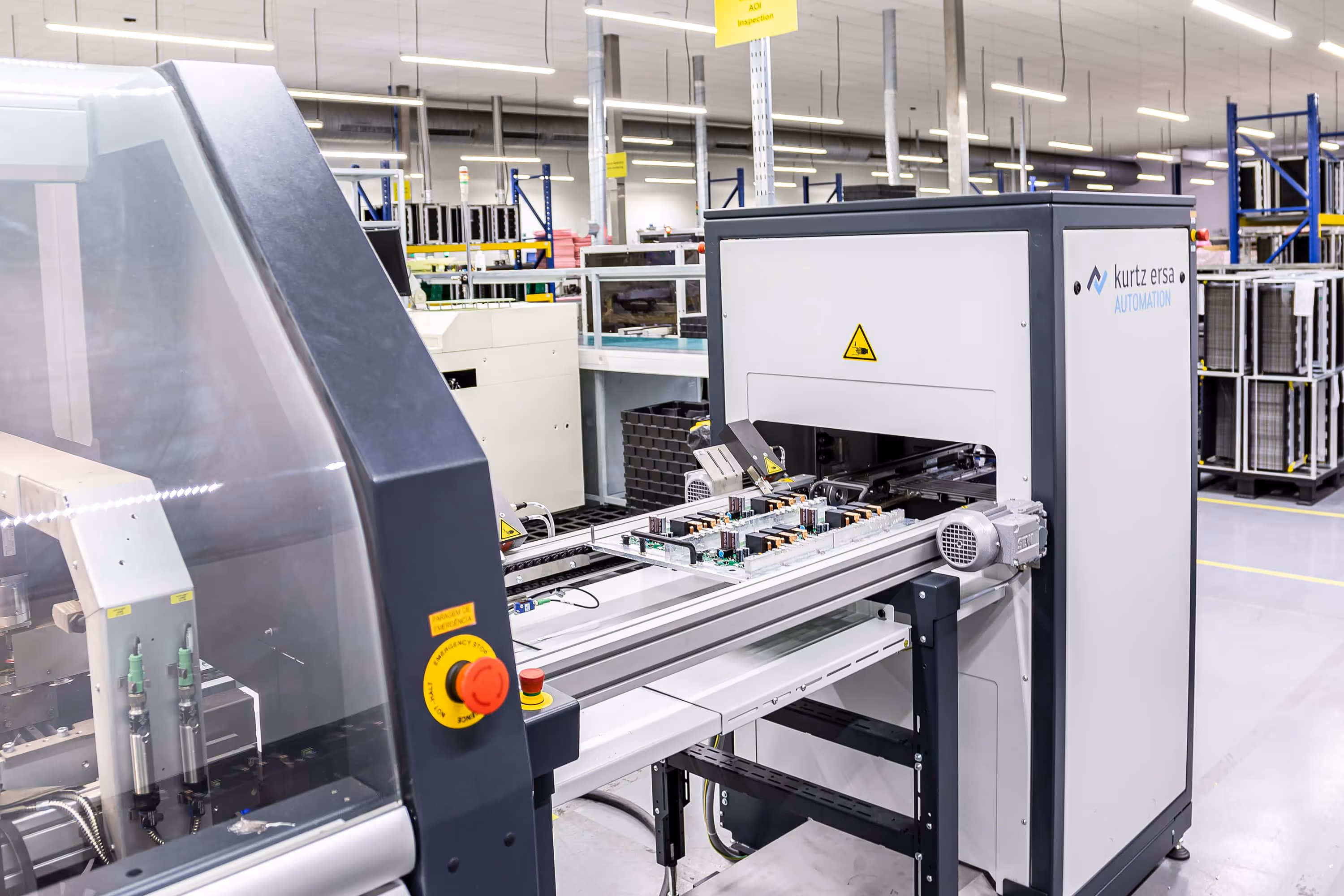Industrial automation machine inspecting electronic circuit boards on a conveyor in a clean factory setting.