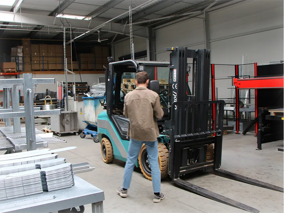 Hugo marche vers un chariot élévateur dans un entrepôt industriel.