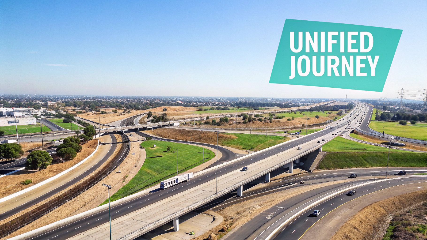 An aerial view of a busy highway interchange with multiple cars, green grass, and a banner saying 'UNIFIED JOURNEY'.