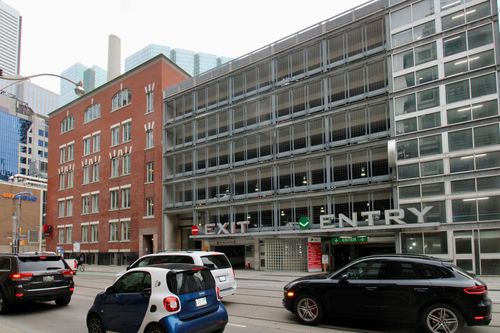 a second back view of the three story commercial building with parked vehicles in the adjacent parking lot.
