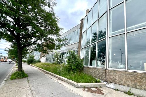 a second back view of the three story commercial building with parked vehicles in the adjacent parking lot.