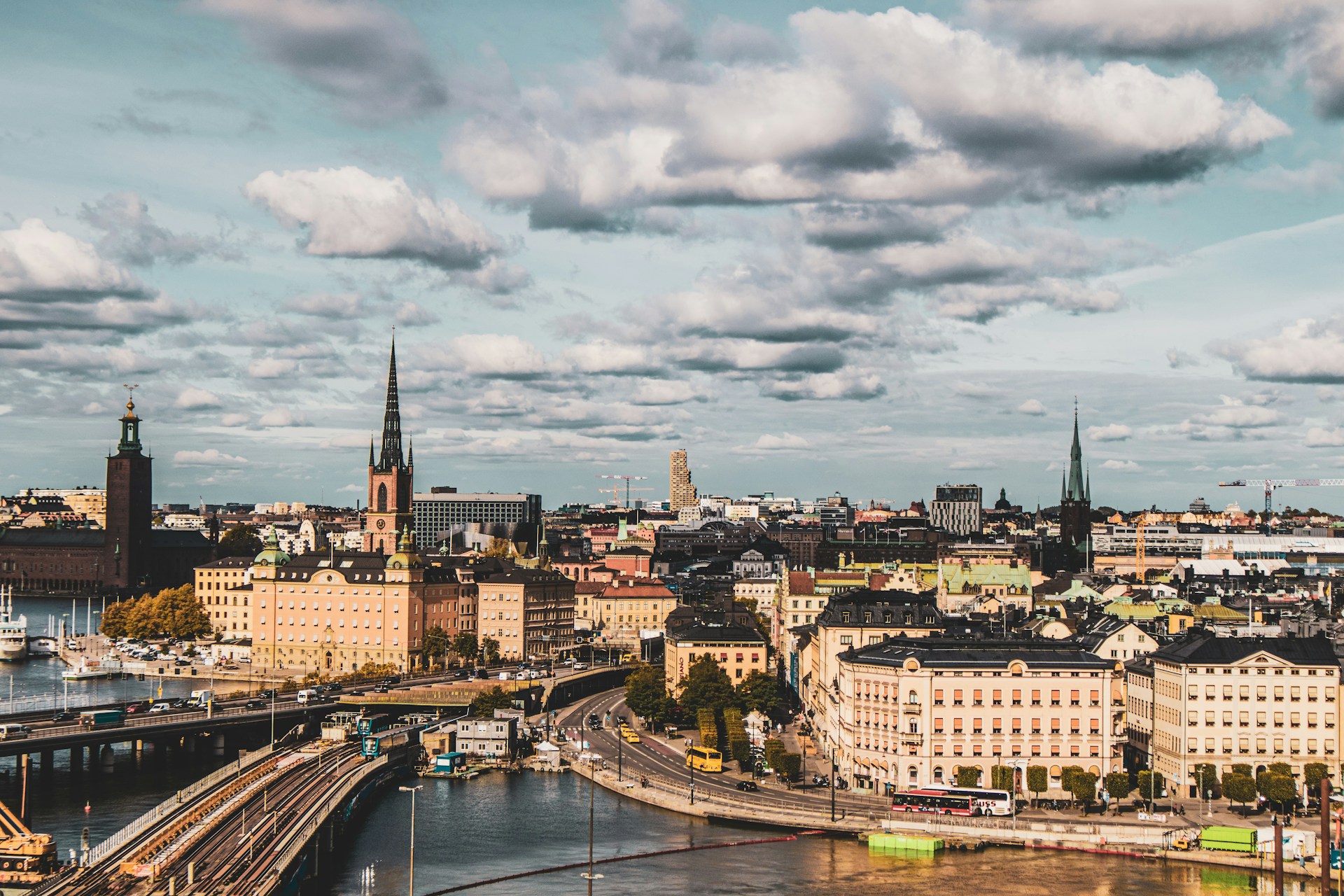 Aerial view of Stockholm, Sweden, showing both new and historical buildings in warm sepia-like tones under a sky with fluffy clouds.