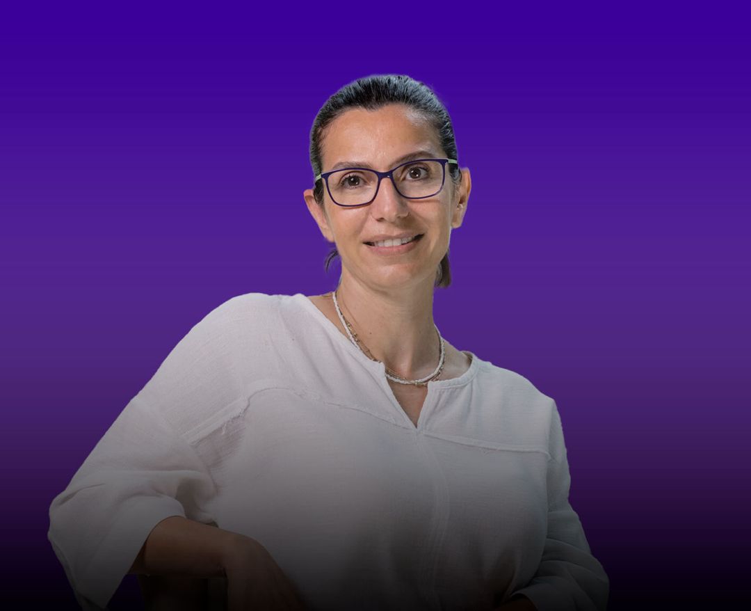 Mor degrade arka plan önünde beyaz bluz giymiş, gözlüklü kadın portresi.