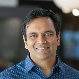 Headshot of a man in a blue patterned shirt smiling