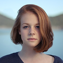 Headshot of a woman with red hair smiling outdoors near water