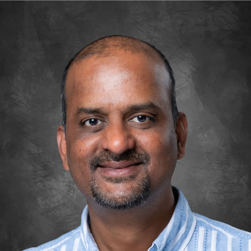 Headshot of Girish, an Intentwise team member, wearing a blue striped shirt