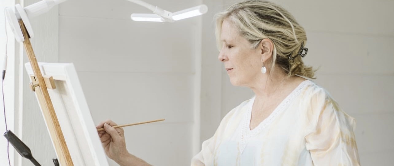 Artist Ann Bailey focusing intently on her canvas while painting with brush and oils at wedding reception