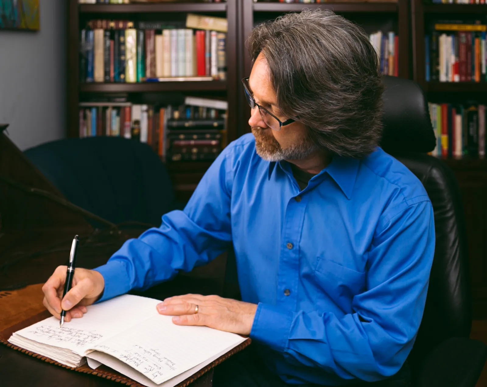 Chuck Coward (The Struggle Coach) seated at desk writing in journal.