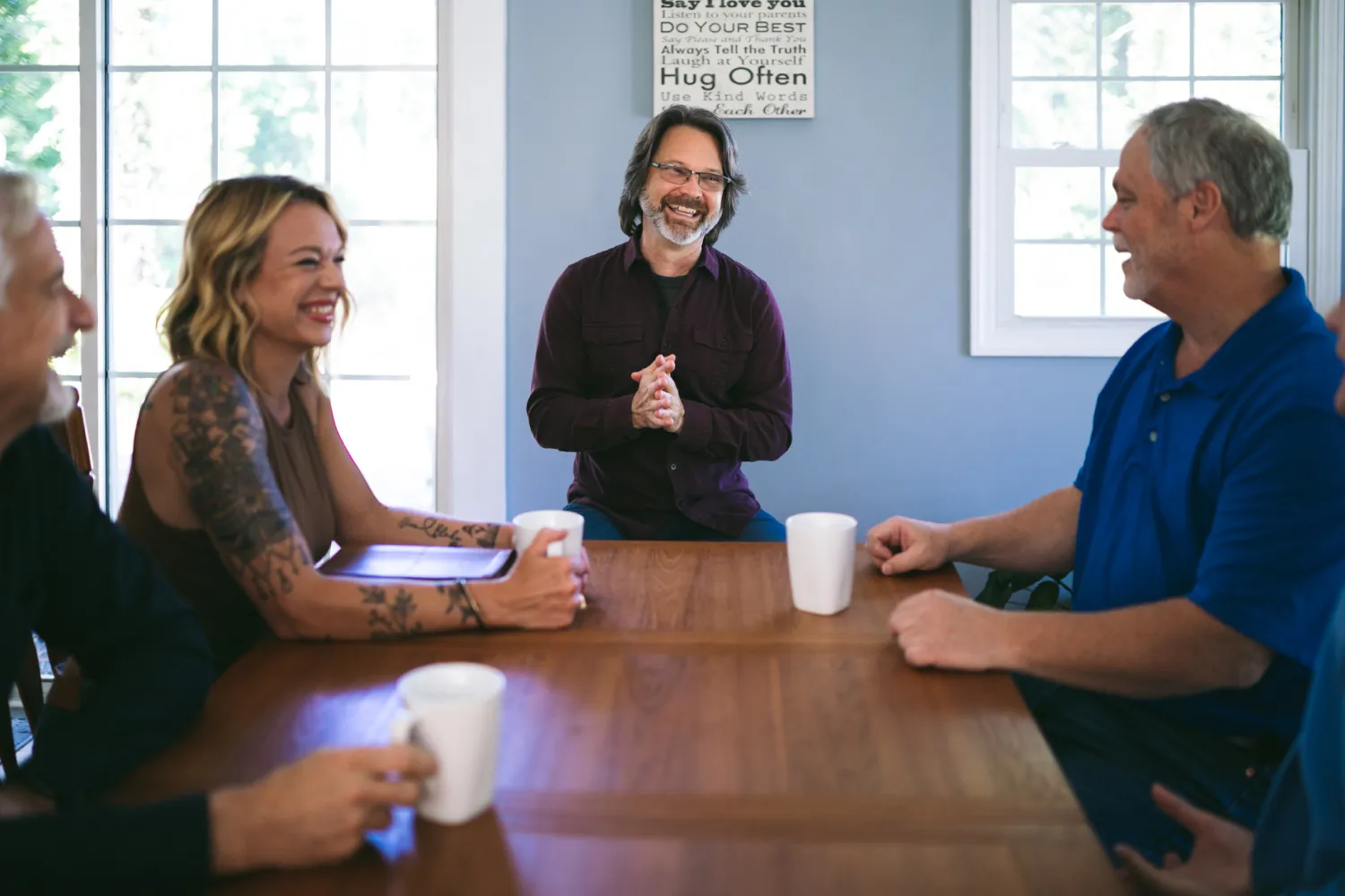 Chuck Coward (The Struggle Coach) seated with a group of people at a kitchen table smiling and enjoying coffee.