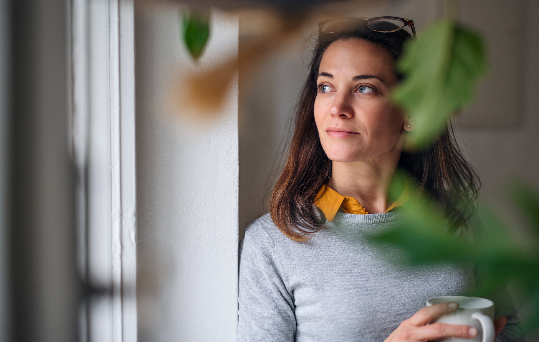 Frau steht am Fenster und denkt ueber Recruiting im Sommerloch nach