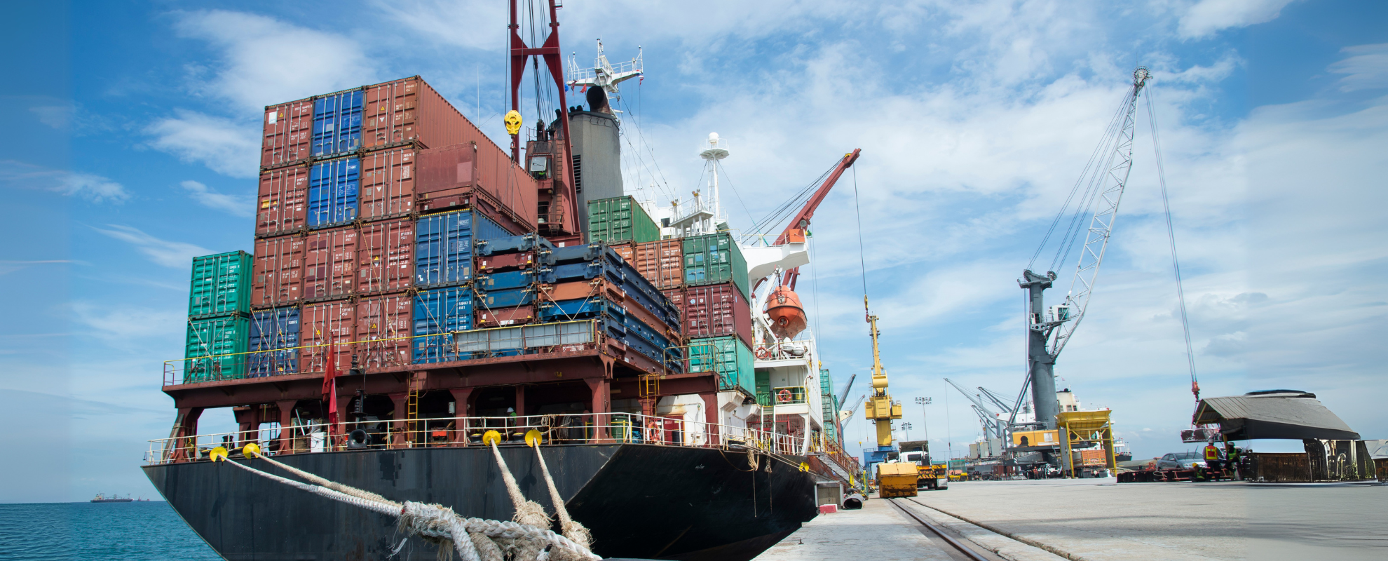 A shipping container laden barge sits dockside