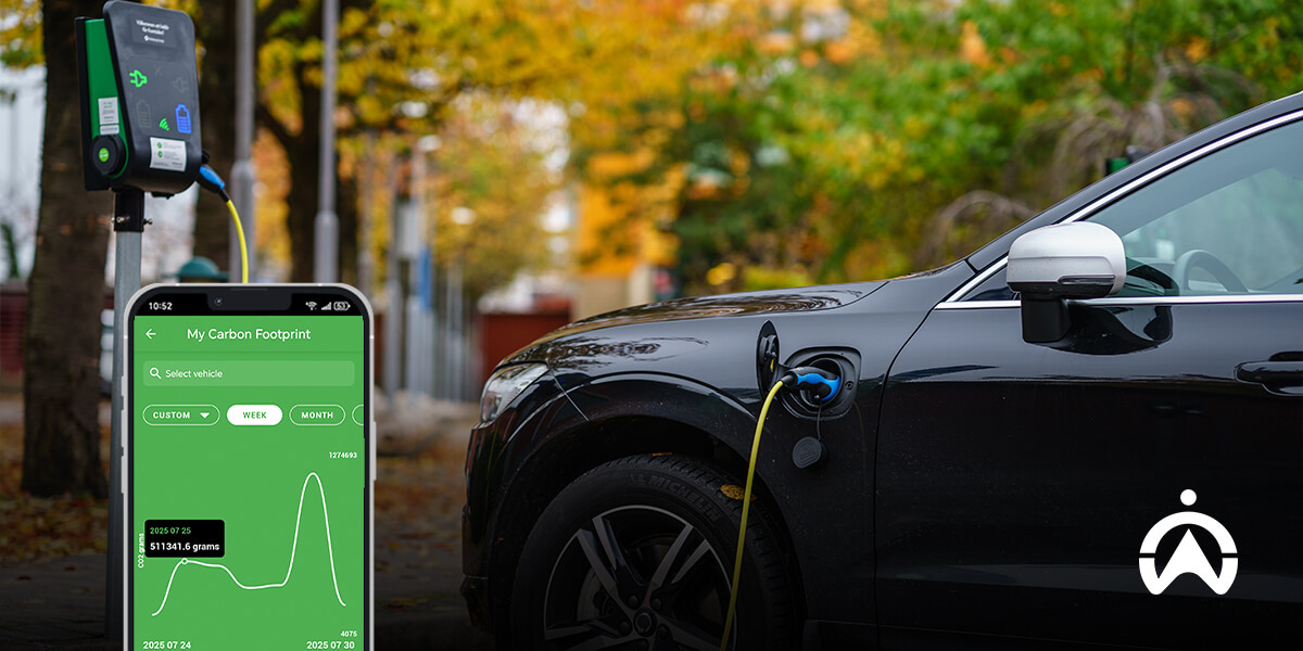 A black electric vehicle charges at a station, while a phone displays carbon footprint data against a backdrop of autumn foliage.