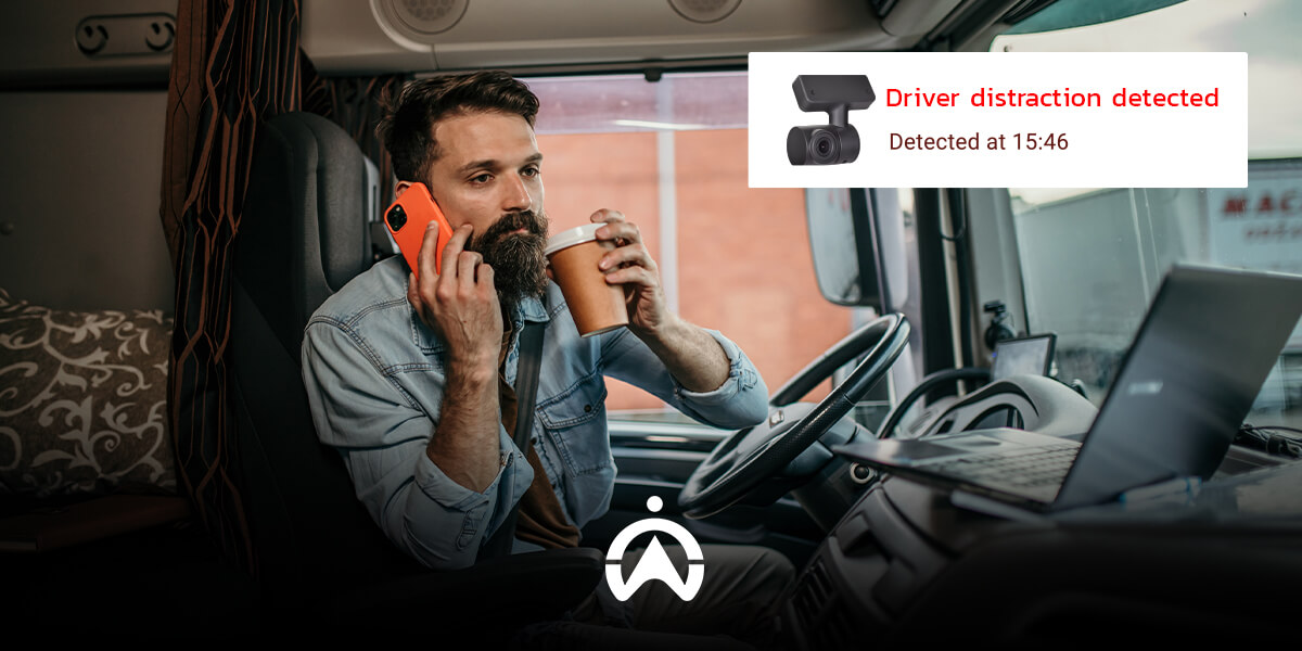 A truck driver multitasks, holding a coffee and phone, while a device alerts of distraction. The cabin has a laptop and modern design.