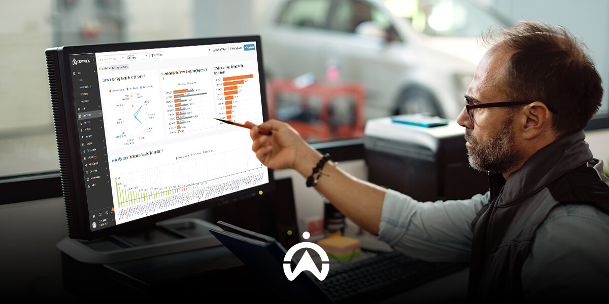 A person pointing at data visualizations on a computer screen, with automotive-related analyses in a workspace setting.