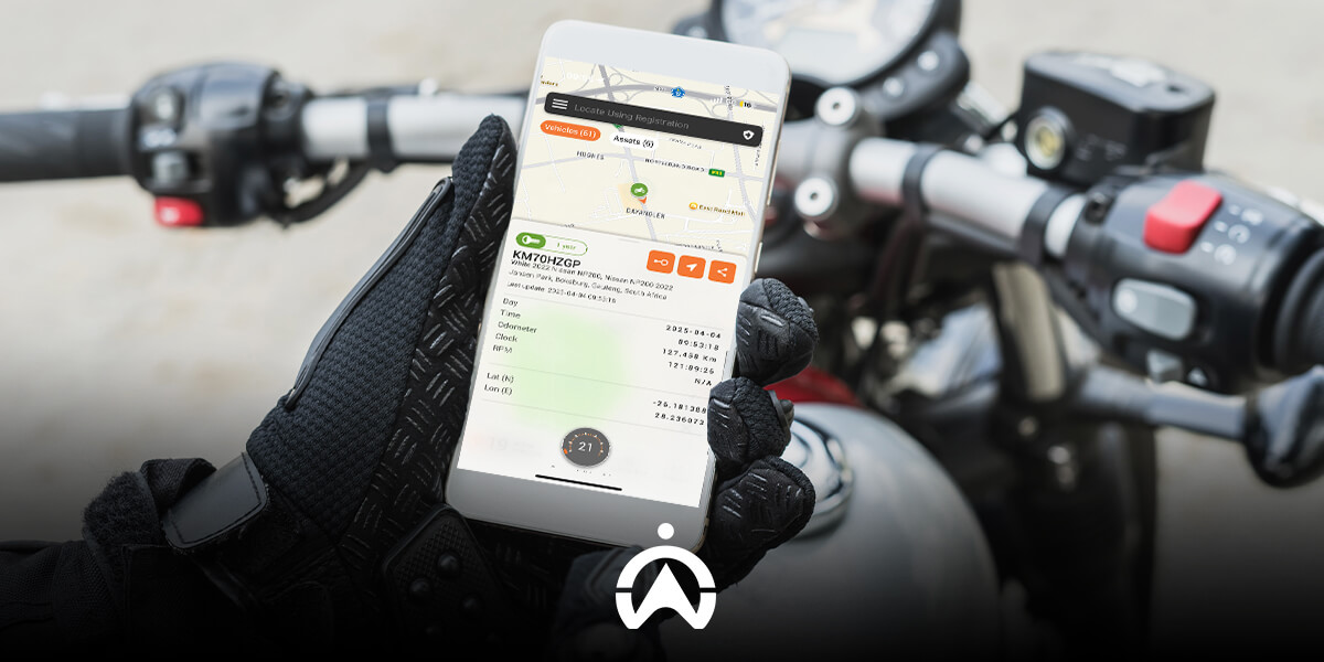 A rider uses a GPS tracking app on a smartphone, positioned above a motorcycle's controls, to monitor vehicle location and data