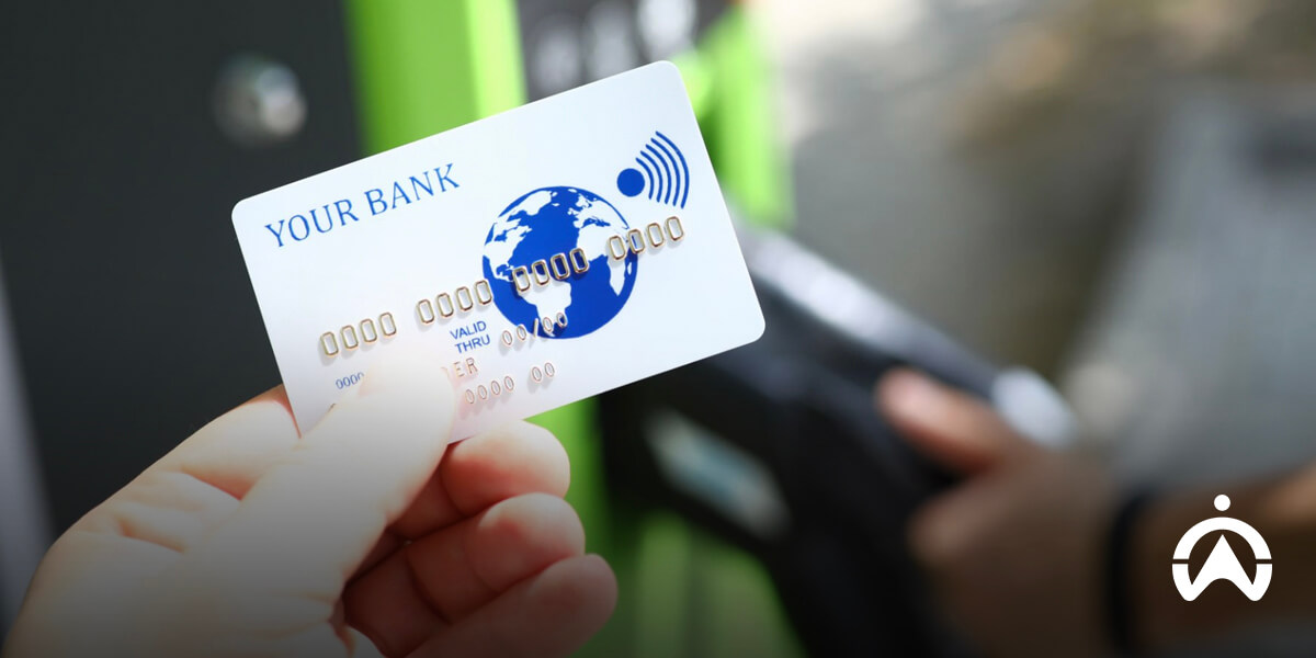Cartrack fleet card vs a fuel card concept with person holding contactless bank card at payment terminal.
