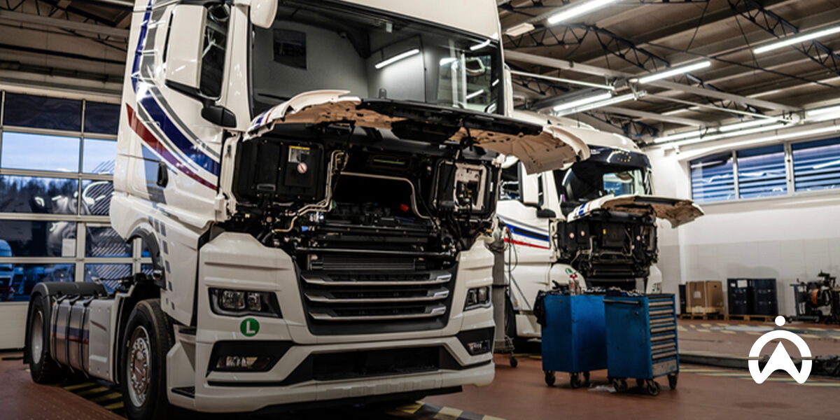 Cartrack fleet utilisation rate shown with two trucks under maintenance in well-lit garage with tools around.